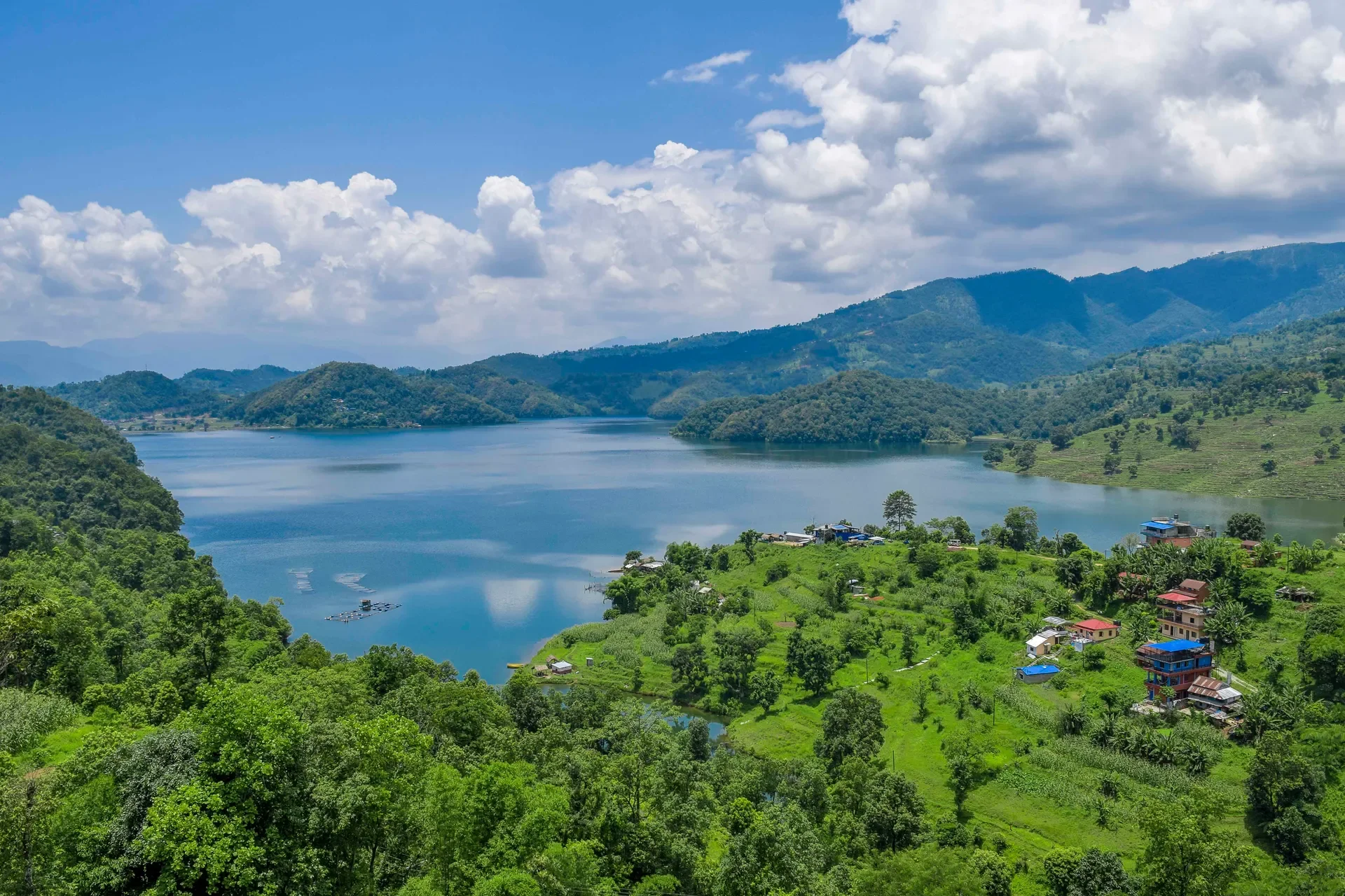 High-angle scenic view of the lush green hills and peaceful blue waters of Begnas Lake in Pokhara.