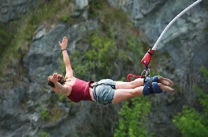 A thrill-seeker diving headfirst while bungee jumping over a deep river gorge in Pokhara.