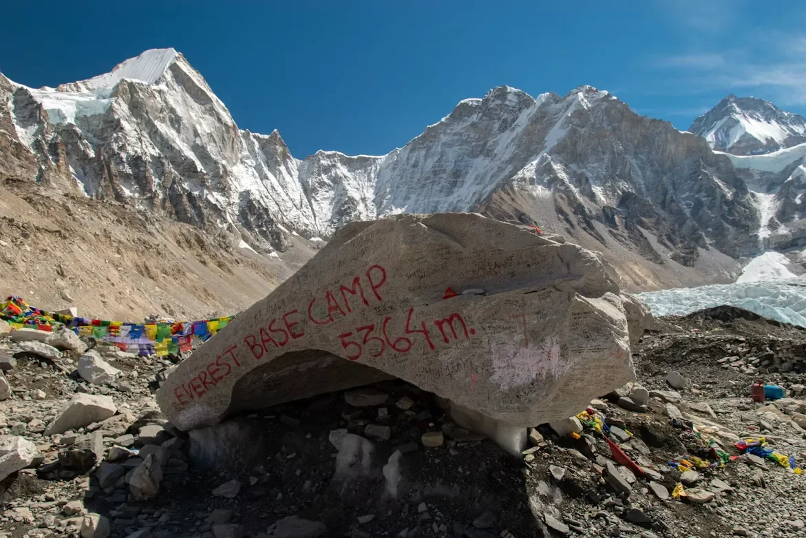 The iconic spray-painted rock milestone decorated with colorful Buddhist prayer flags marking Everest Base Camp.