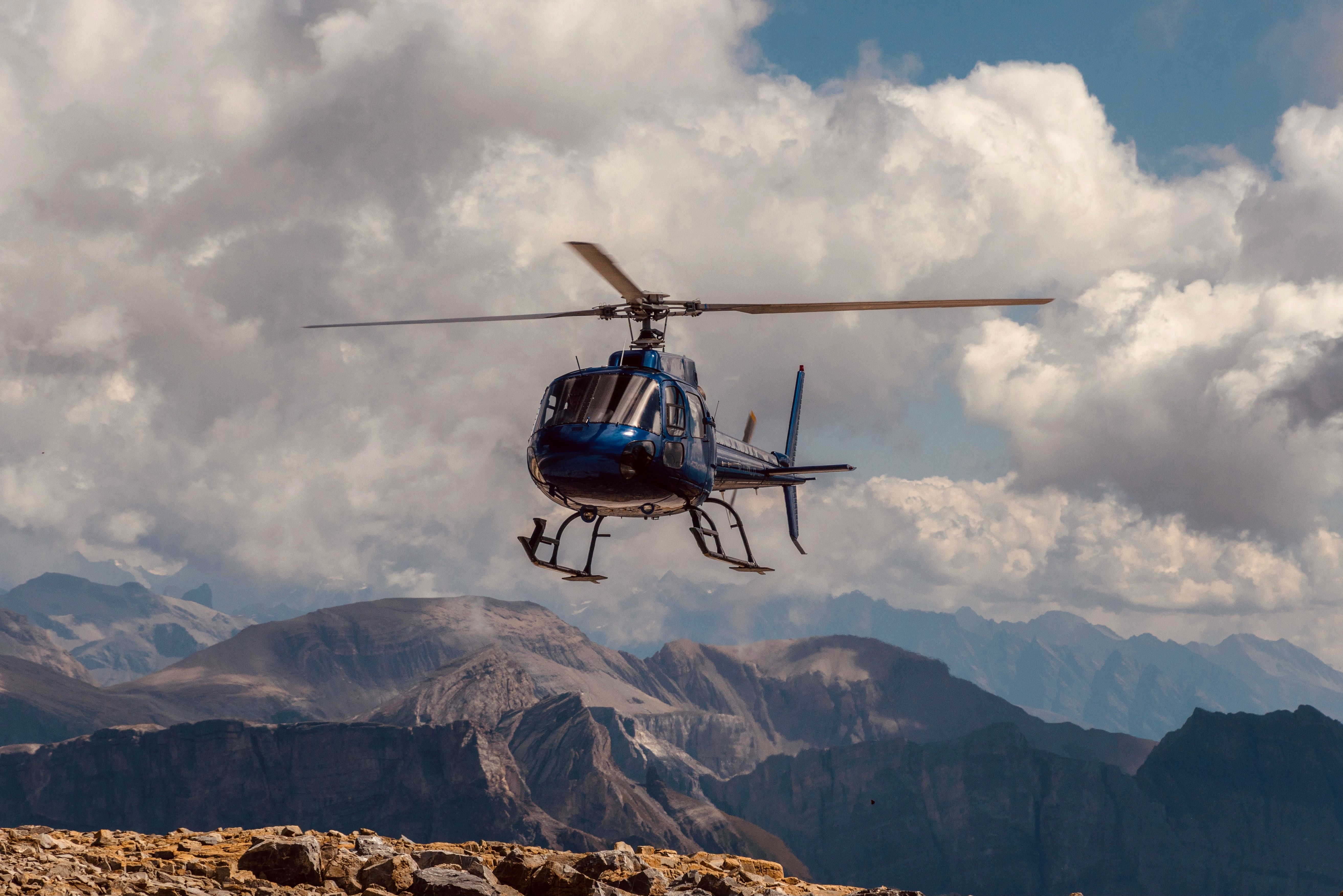 Helicopter taking off from a high-altitude landing pad surrounded by Himalayan peaks.