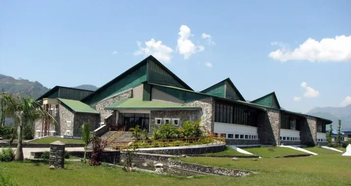 Modern stone and green-roof architecture of the International Mountain Museum in Pokhara under a clear sky.