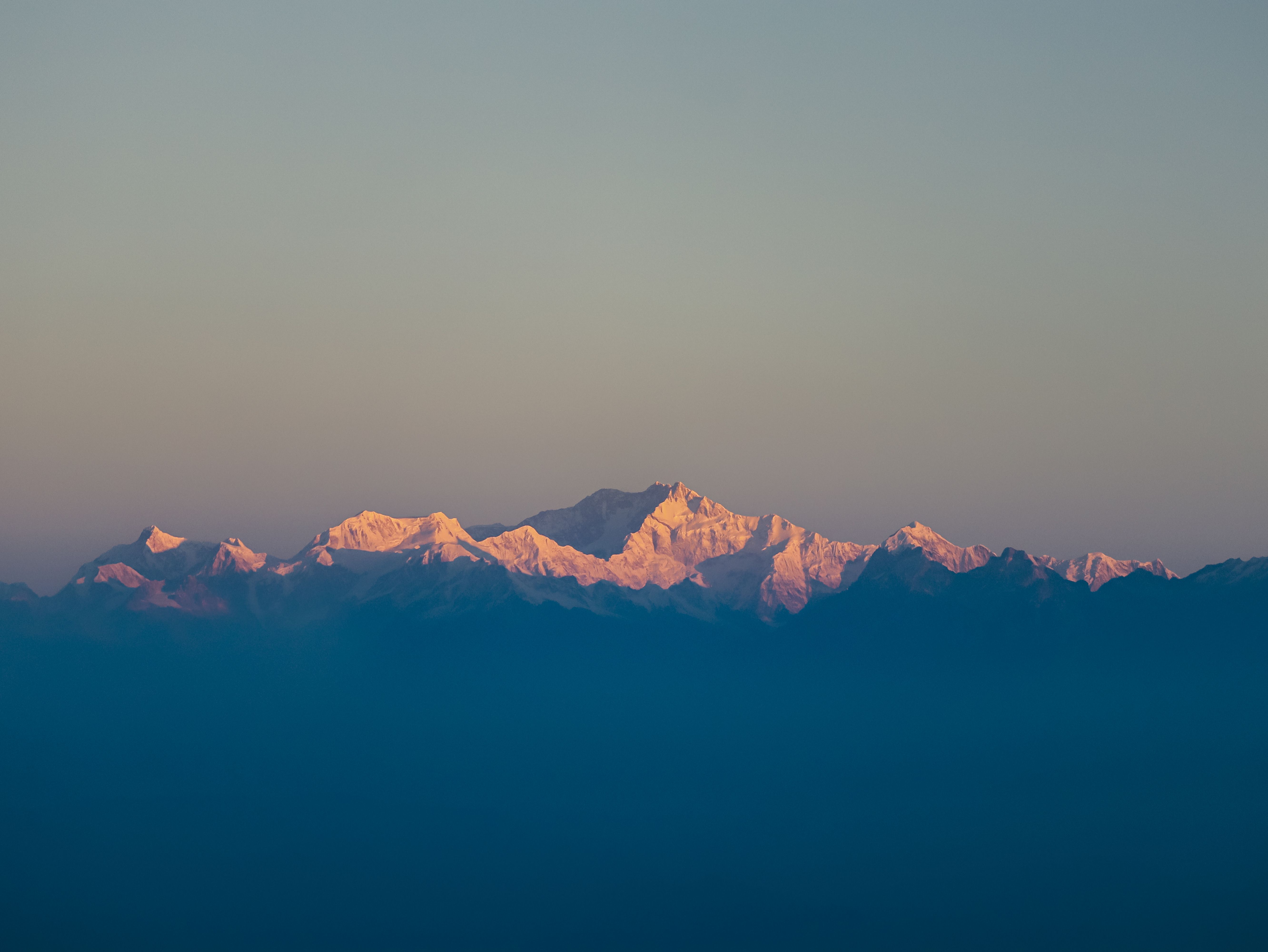 The expansive Kanchenjunga mountain range glowing in the bright daylight.