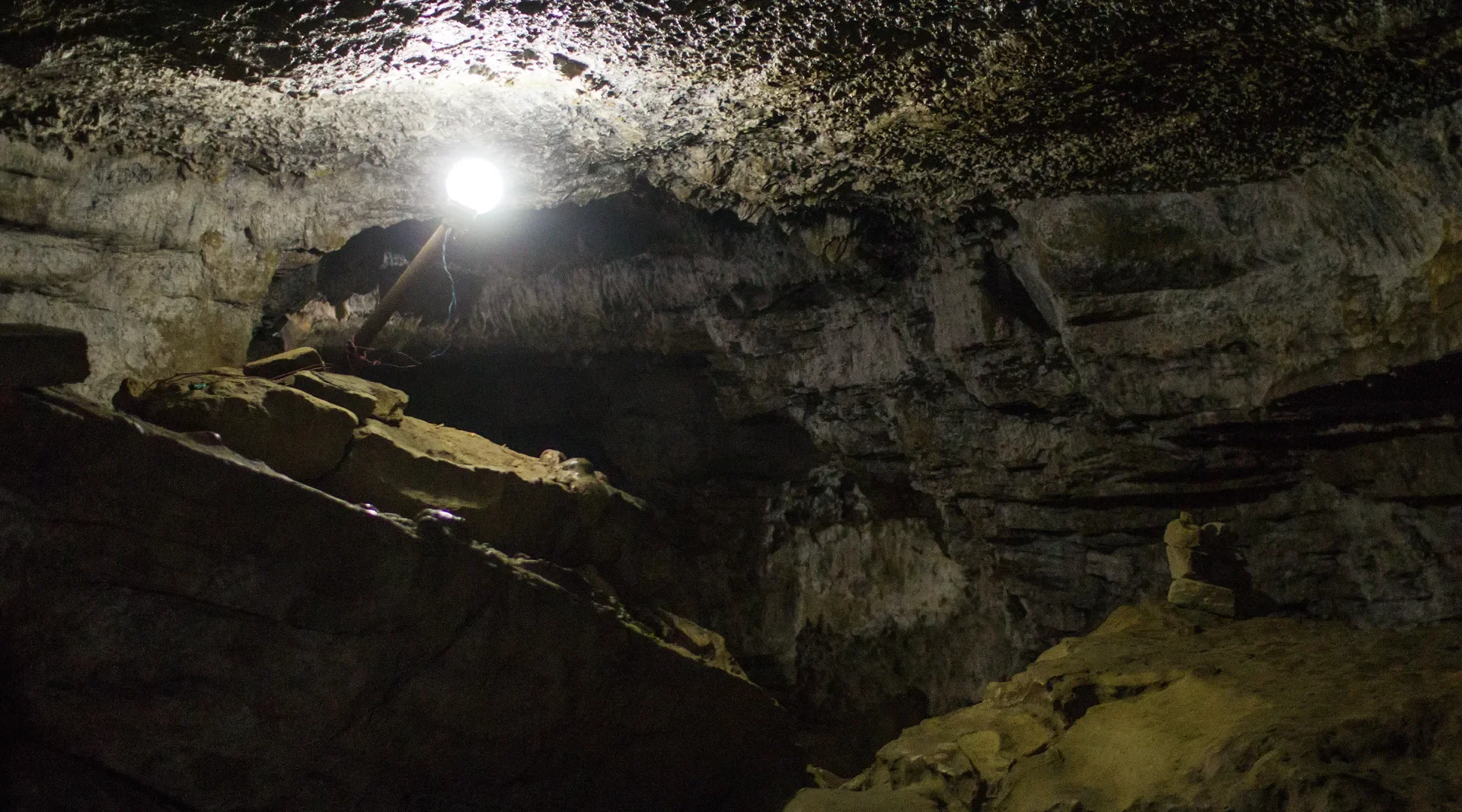 The dark, limestone interior of Mahendra Cave in Pokhara illuminated by a single artificial bulb.