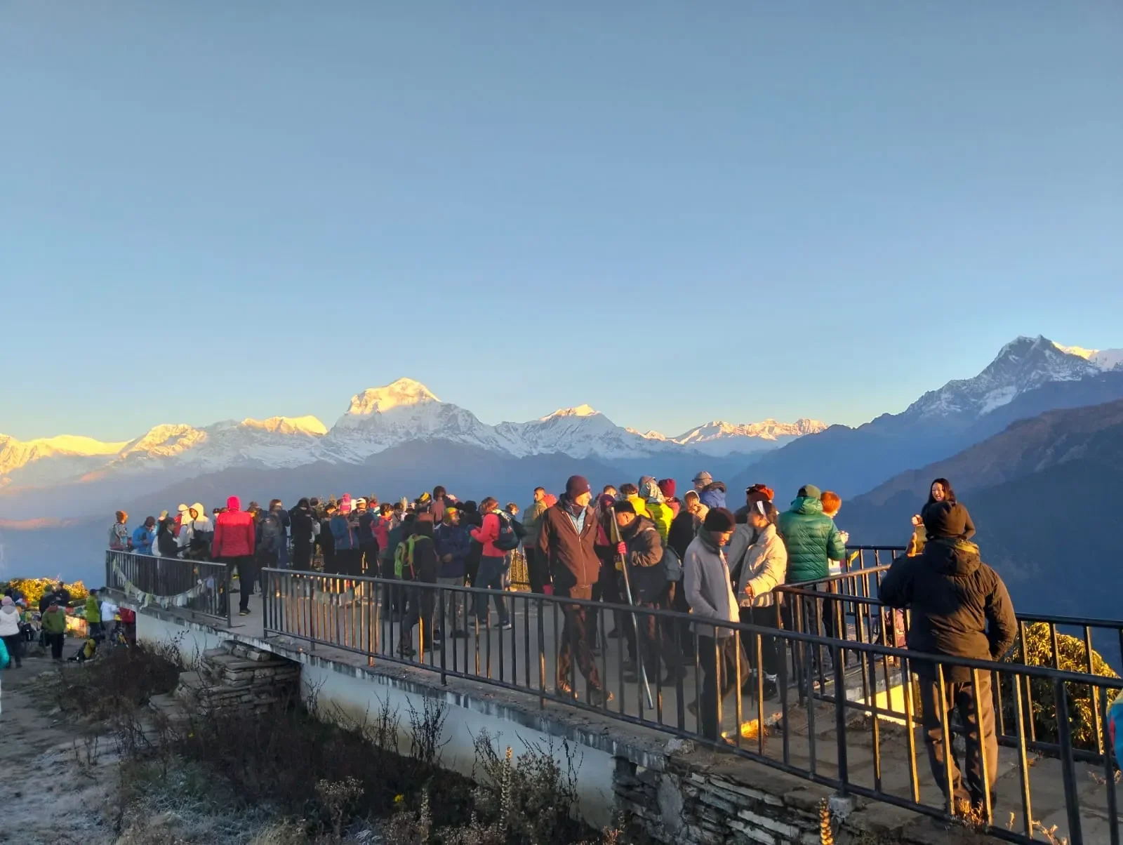 Tourists and trekkers gathered at the Poon Hill viewpoint tower watching the sunrise over the Himalayan mountain range