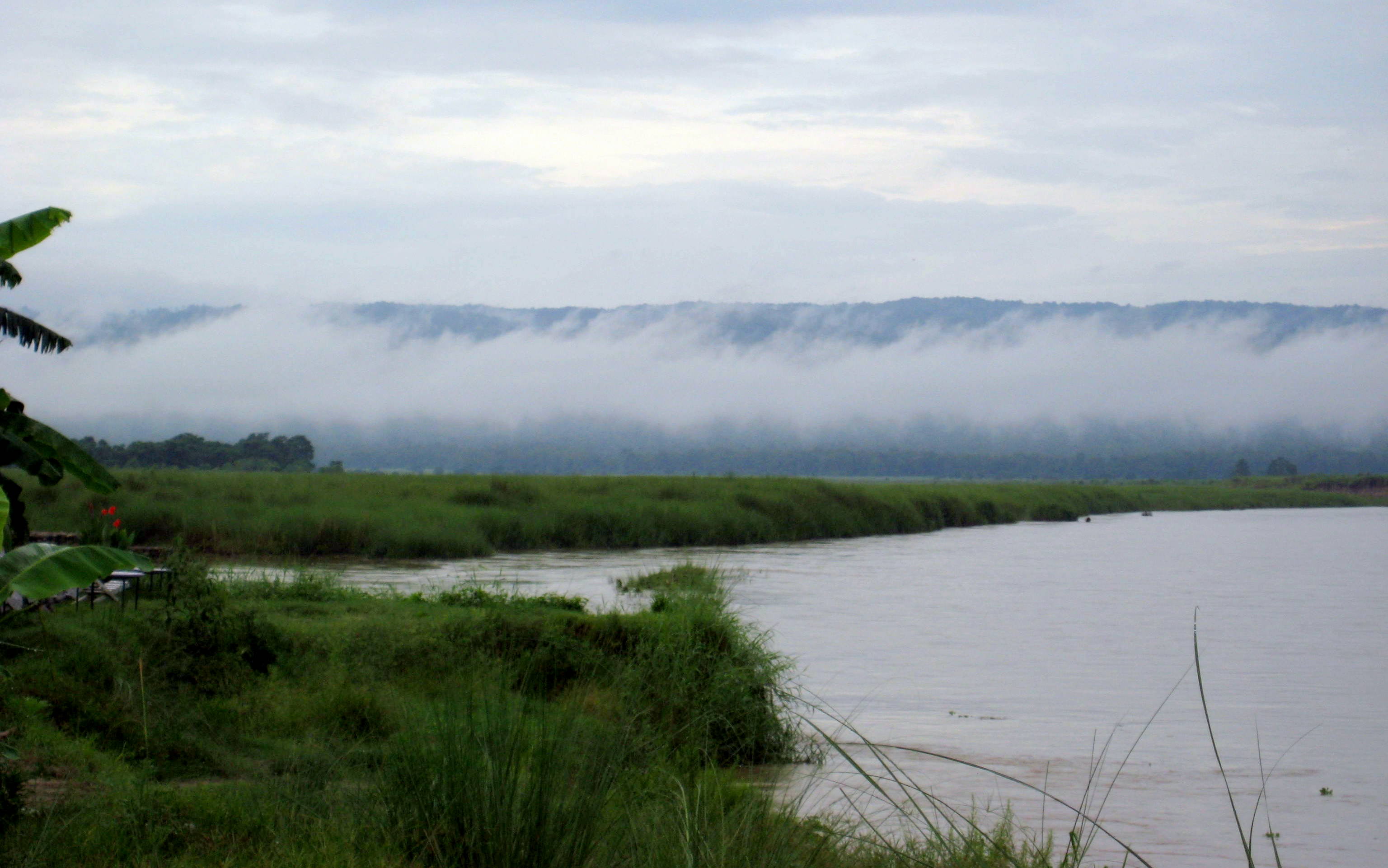 Scenic view of the calm East Rapti River flowing past Sauraha village, the main hub for Chitwan safaris.