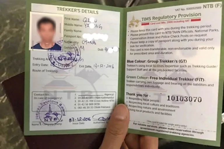 Close-up of an official green Nepal TIMS card permit booklet showing trekker details and regulatory provisions issued by the Nepal Tourism Board
